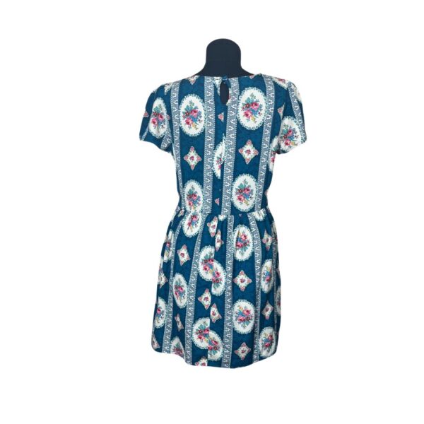 Tirkizna šarena haljina sa cvetnim motivima, kratkim rukavima i elastičnim strukom, prikazana s zadnje strane, veličina S.