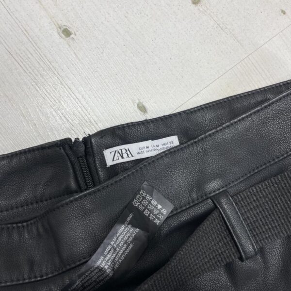 Crna kožna mini suknja iz Zare sa kaišem, prikazana na svetloj podlozi.